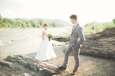 Yakışıklı romantik damat ve güzel gelin Nehri manzaralı dağlarında yakınında poz