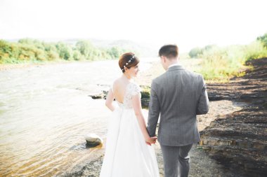 Zarif nazik şık damat ve gelin taşlarla Nehri yakınında. Evlilik çift aşık