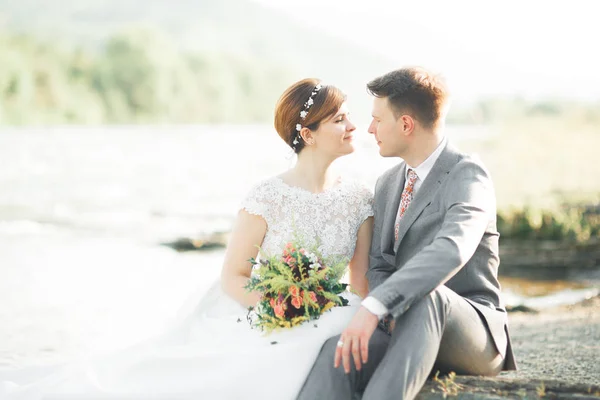 Sposa e sposo in possesso di bel bouquet da sposa. Posa vicino al fiume — Foto Stock