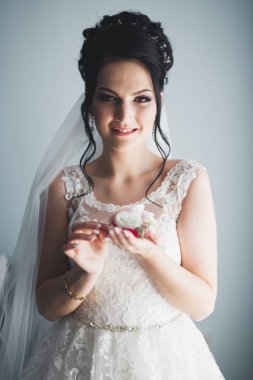 Cüppeli muhteşem gelin bir odada düğün töreni için poz veriyor ve hazırlanıyor.