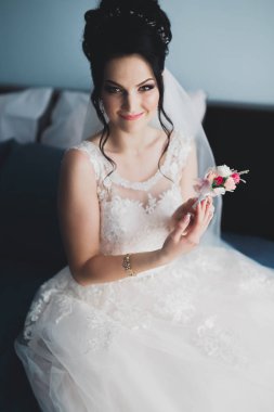 Cüppeli muhteşem gelin bir odada düğün töreni için poz veriyor ve hazırlanıyor.