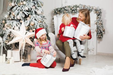 Anne ve çocukları Noel ağacının yanında kutluyorlar.