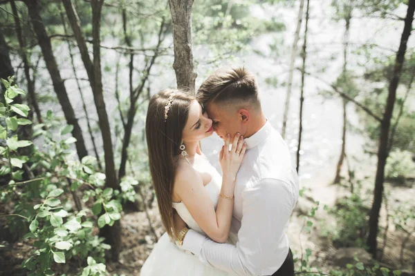 Casamento casal homem, noiva beijando e abraçando em um fundo do rio, montanhas. Retrato de beleza — Fotografia de Stock