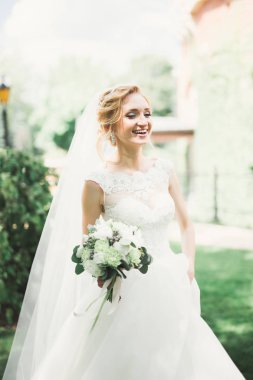 Gelin çiçekli büyük ve güzel bir düğün buketi tutuyor.