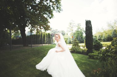 Parkta poz veren zarif beyaz elbiseli güzel gelin.