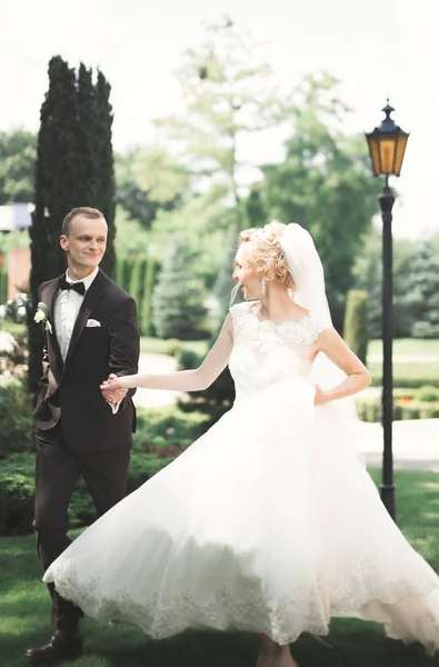 Yeni evli çiftimiz düğün günlerinde ellerinde buketle parkta yürüyorlar. — Stok fotoğraf