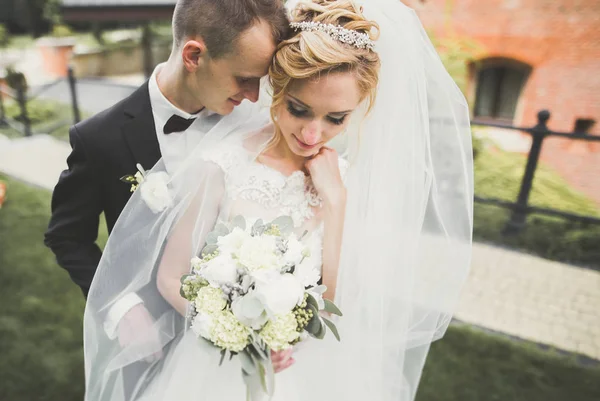 Ravissant couple de mariage heureux, mariée avec longue robe blanche posant dans la belle ville — Photo