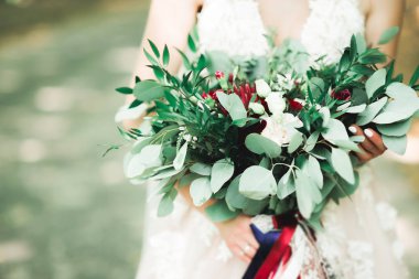 Gelin çiçekli büyük ve güzel bir düğün buketi tutuyor.