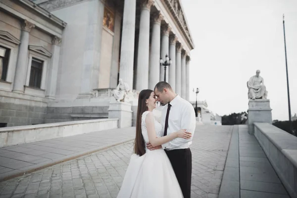 Прекрасные невеста и жених обнимаются и целуются на улице в день своей свадьбы — стоковое фото