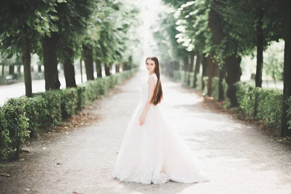 Bela noiva em elegante vestido branco segurando buquê posando no parque — Fotografia de Stock