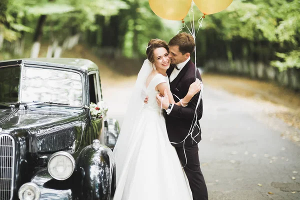 Güzel yeni evli çift siyah arabanın yanında poz veriyor. — Stok fotoğraf