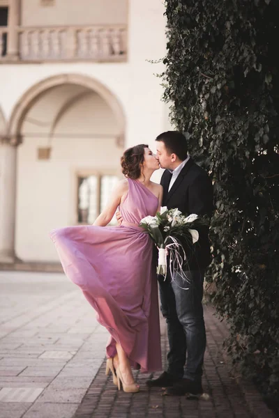 Gyönyörű pár, ember, lány, rózsaszín hosszú ruhában pózol a régi kastély közelében oszlopai. Krakkó Vavel — Stock Fotó