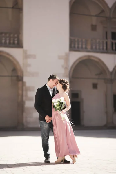Hermosa pareja, hombre, chica con vestido largo de color rosa posando en el viejo castillo cerca de columnas. Cracovia Vavel — Foto de Stock