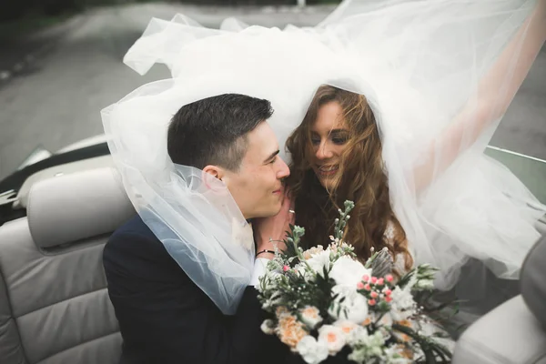 Stylish wedding couple, bride, groom kissing and hugging on retro car — Stock Photo, Image