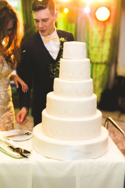 Gelin ve damat düğün pastasını kesiyor.