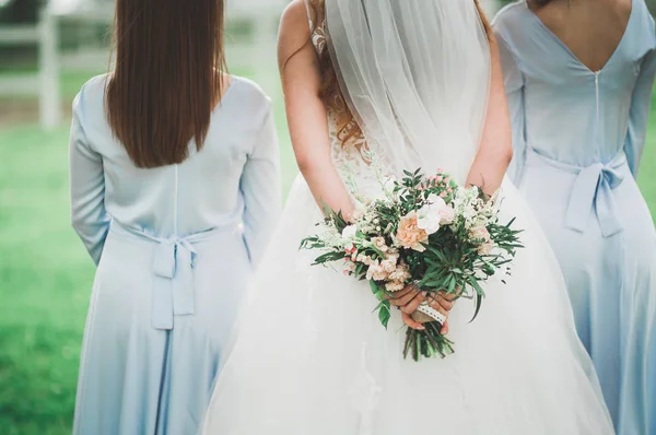 La novia y las damas de honor están mostrando hermosas flores en sus manos —  Fotos de Stock