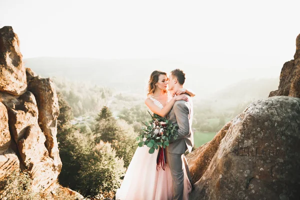 Unga nygifta par, brud och brudgum kyssas, kramas på perfekt utsikt över bergen, blå himmel — Stockfoto