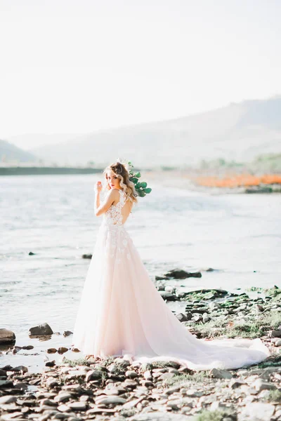 Krásná módní nevěsta ve svatebních šatech pózuje v blízkosti řeky — Stock fotografie