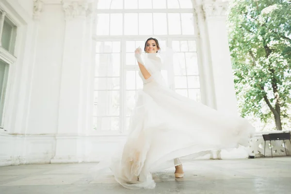 Mooie bruid in trouwjurk met lange volledige rok, witte achtergrond, dansen en lachen — Stockfoto