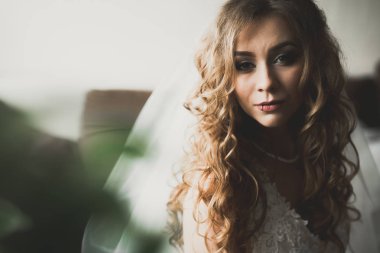 Cüppeli muhteşem gelin bir odada düğün töreni için poz veriyor ve hazırlanıyor.