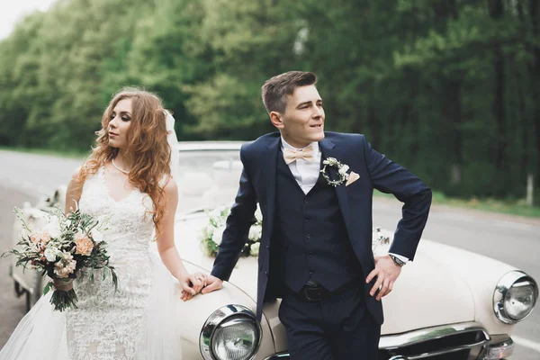 Casal de casamento elegante, noiva, noivo beijando e abraçando no carro retro — Fotografia de Stock