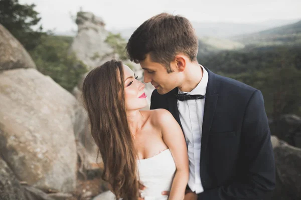 新婚夫妇在美丽的风景下亲吻和拥抱在岩石旁 — 图库照片