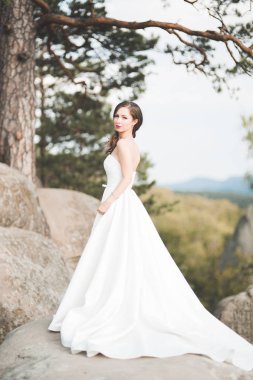 Güzel gelin orman kayalar ile poz bir buket ile. Açık havada