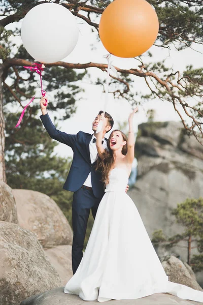 Boldog esküvői pár csók, és átölelte a következő látnivaló közelében: magas szikla — Stock Fotó