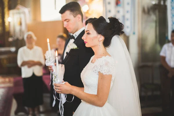 Bröllopspar bida och brudgum gifta sig i en kyrka — Stockfoto