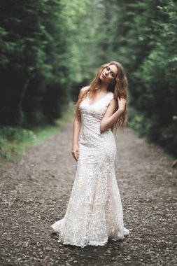 Parkta poz veren zarif beyaz elbiseli güzel gelin.