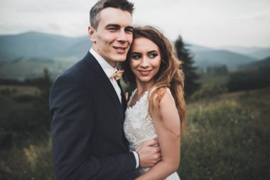 Güzel dağlarda poz veren mutlu bir düğün çifti.