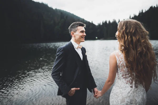 Joven pareja recién casada, novia y novio besándose, abrazándose a la vista perfecta de las montañas, cielo azul —  Fotos de Stock