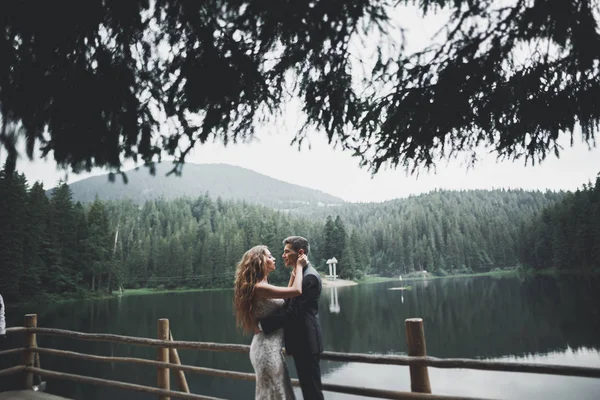 Hermosa pareja de boda besándose y abrazándose cerca de la montaña con vista perfecta —  Fotos de Stock