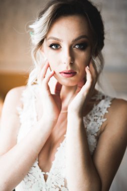 Cüppeli muhteşem gelin bir odada düğün töreni için poz veriyor ve hazırlanıyor.