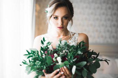 Cüppeli muhteşem gelin bir odada düğün töreni için poz veriyor ve hazırlanıyor.