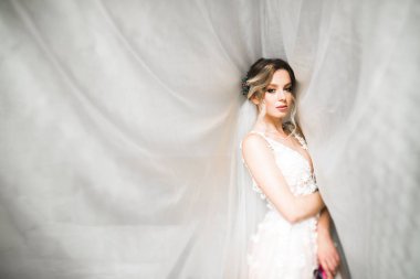 Cüppeli muhteşem gelin bir odada düğün töreni için poz veriyor ve hazırlanıyor..