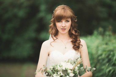 Çekici gelinin portresi, uzun saçlı, büyük buketli poz veren.