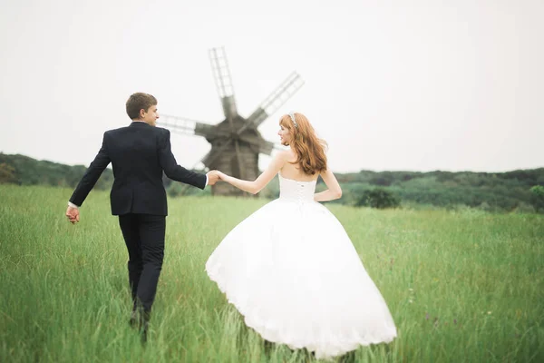 Elegante pareja de recién casados felices caminando en el parque el día de su boda con ramo —  Fotos de Stock