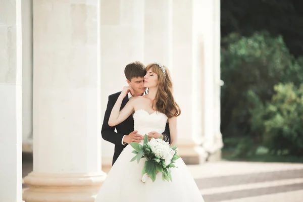 Preciosa pareja feliz boda, novia con vestido blanco largo posando en la hermosa ciudad — Foto de Stock