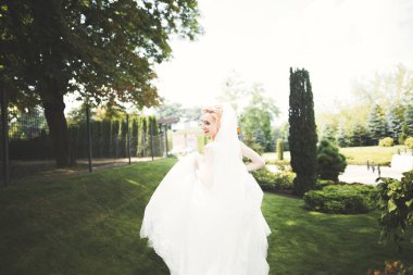 Parkta poz veren zarif beyaz elbiseli güzel gelin.