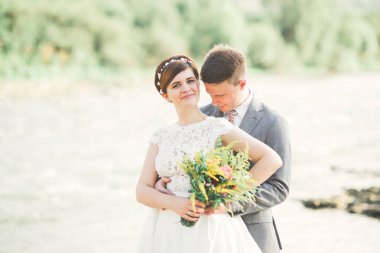 Zarif nazik şık damat ve gelin taşlarla Nehri yakınında. Evlilik çift aşık