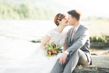 Zarif nazik şık damat ve gelin taşlarla Nehri yakınında. Evlilik çift aşık