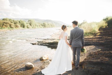 Gelin ve damat güzel düğün buket tutarak. Nehir kenarında poz