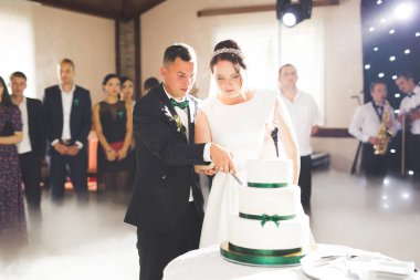 Gelin ve damat düğün pastasını kesiyor.