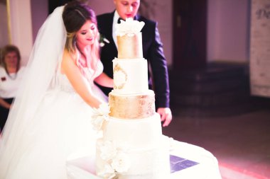 Gelin ve damat düğün pastasını kesiyor.