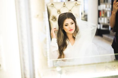 Cüppeli muhteşem gelin bir odada düğün töreni için poz veriyor ve hazırlanıyor.