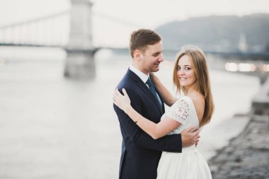 Zarif, şık, mutlu, sarışın gelin ve güzel bir nehrin arka planında muhteşem damat.