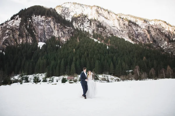 Щаслива пара біжить тримаючись за руки взимку на тлі гір — стокове фото