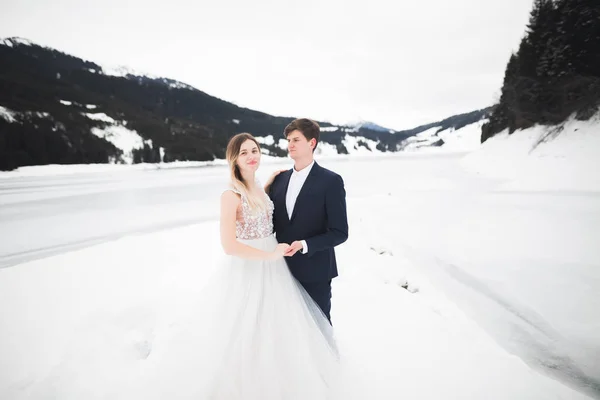 Jeune couple romantique regardant loin, vue arrière, lac et montagnes d'hiver sur fond — Photo