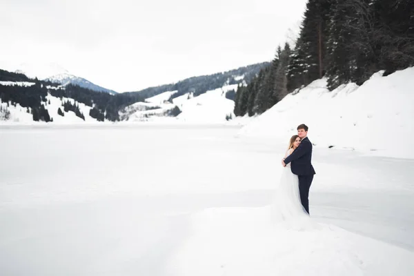 Schönes junges Paar in den Winterbergen. Winterwanderung der Verliebten. Mann umarmt Frau — Stockfoto
